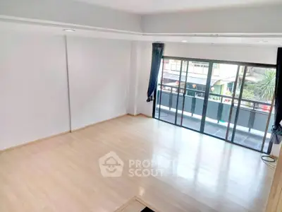 Spacious living room with large windows and wooden flooring, offering ample natural light and a modern feel.