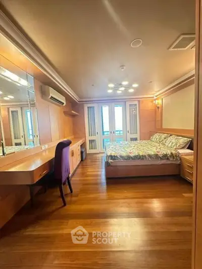 Spacious bedroom with wooden flooring and modern furnishings in a luxury apartment.