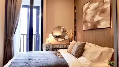 Cozy bedroom with modern decor and balcony access, featuring elegant lighting and stylish artwork.