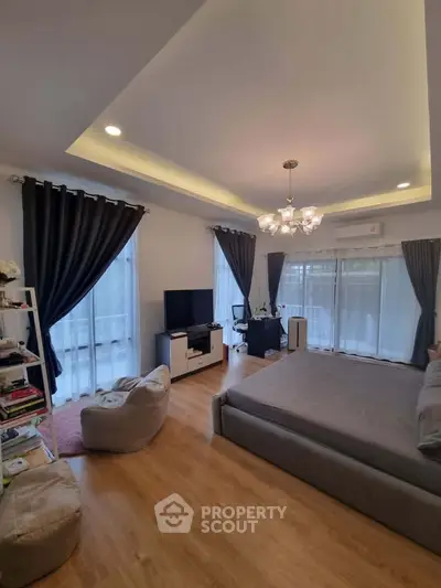 Spacious bedroom with modern decor, featuring a cozy seating area and large windows for natural light.