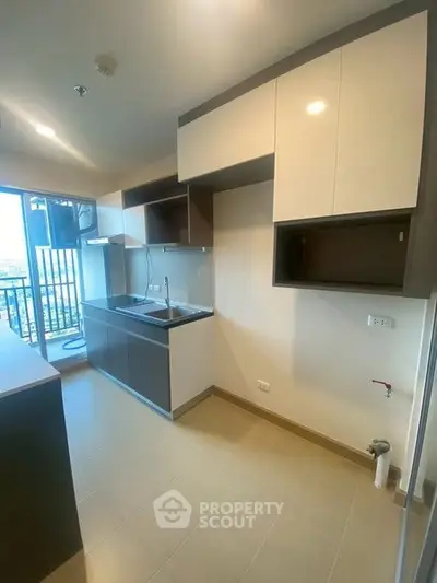 Modern kitchen with sleek cabinetry and balcony view in urban apartment