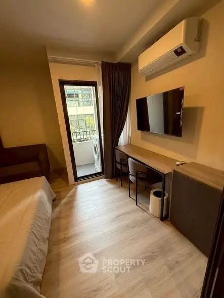 Cozy bedroom with balcony access, featuring modern air conditioning and wall-mounted TV.