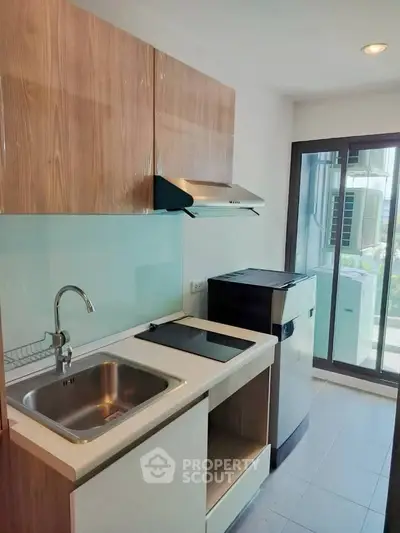 Modern kitchen with sleek cabinetry and glass backsplash in a bright apartment.