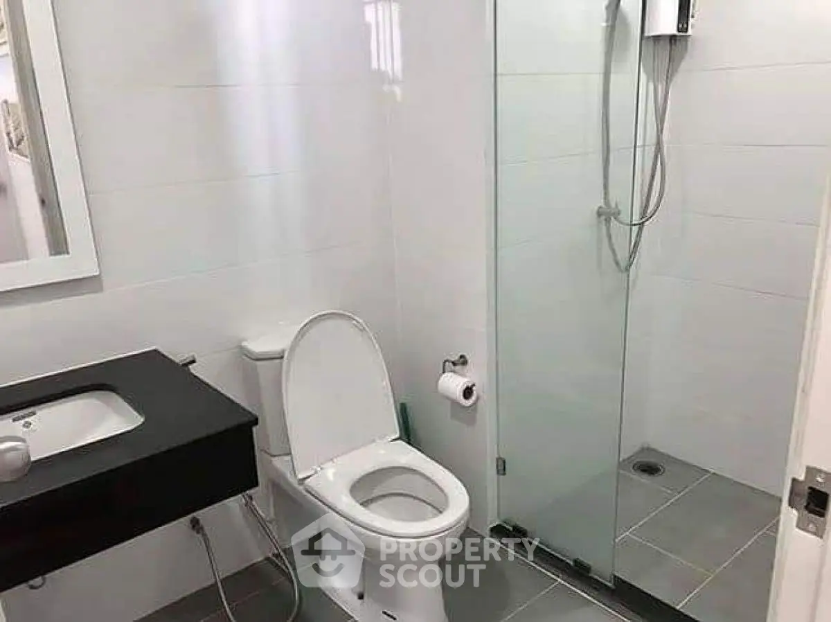 Modern bathroom with glass shower and sleek black vanity.