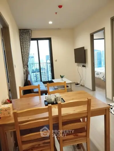 Modern apartment interior with dining area and living room, featuring a city view from the balcony.