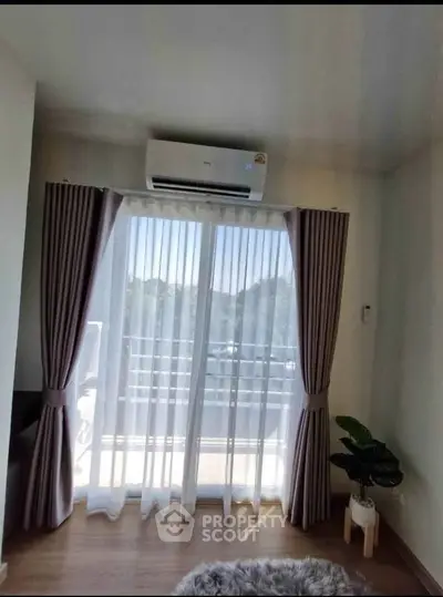 Bright living room with large window and air conditioning, featuring elegant curtains and a cozy rug.