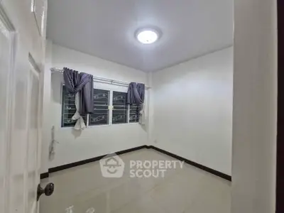 Spacious unfurnished bedroom with tiled flooring and large window, perfect for customization.