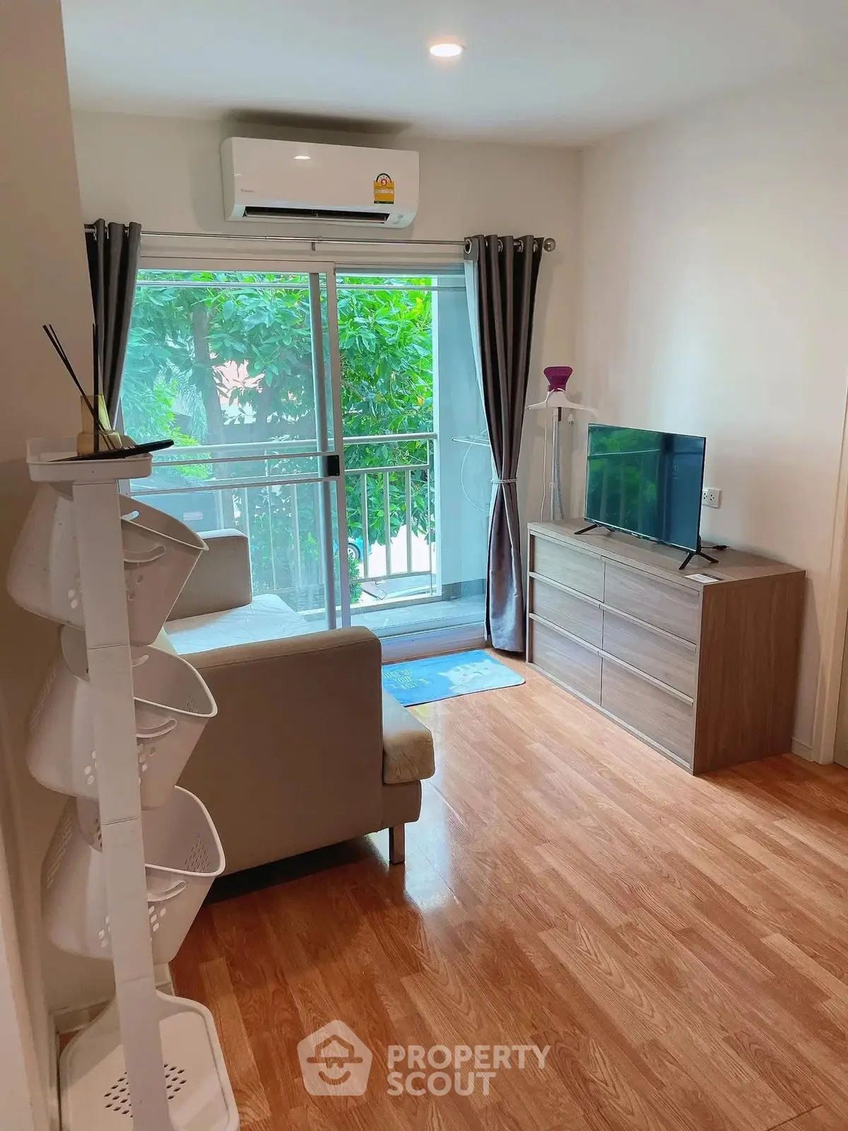 Cozy living room with balcony view, modern furniture, and wooden flooring in a bright apartment.