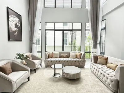 Luxurious high-ceiling living room with elegant furniture and large windows