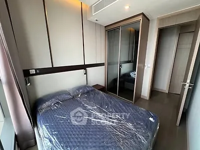Modern bedroom with sleek design and mirrored closet doors in a high-rise apartment.
