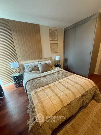 Cozy bedroom with stylish decor and wooden flooring, featuring a comfortable bed and elegant lighting.