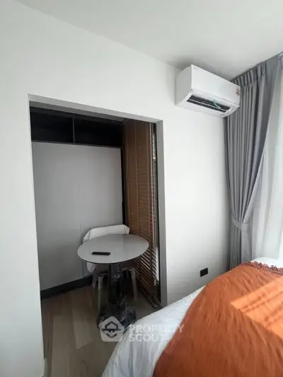 Cozy bedroom with modern air conditioning and stylish decor, featuring a small study nook.