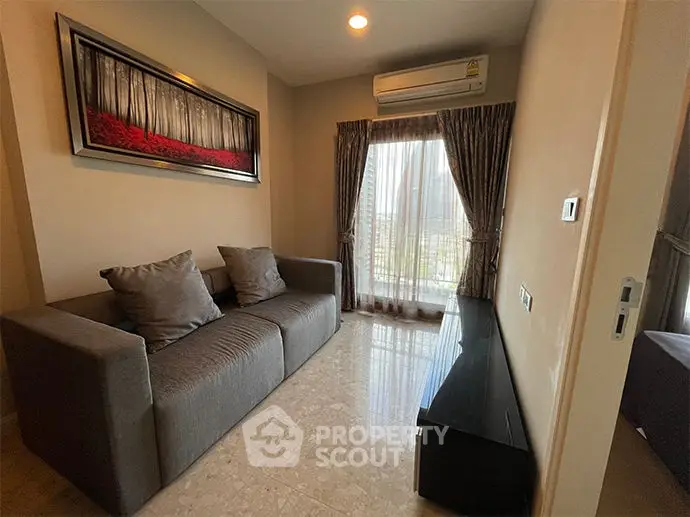 Cozy living room with modern sofa and large window offering natural light and city view.
