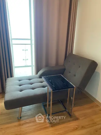 Stylish modern living room with chic chaise lounge and sleek side table near a bright window.