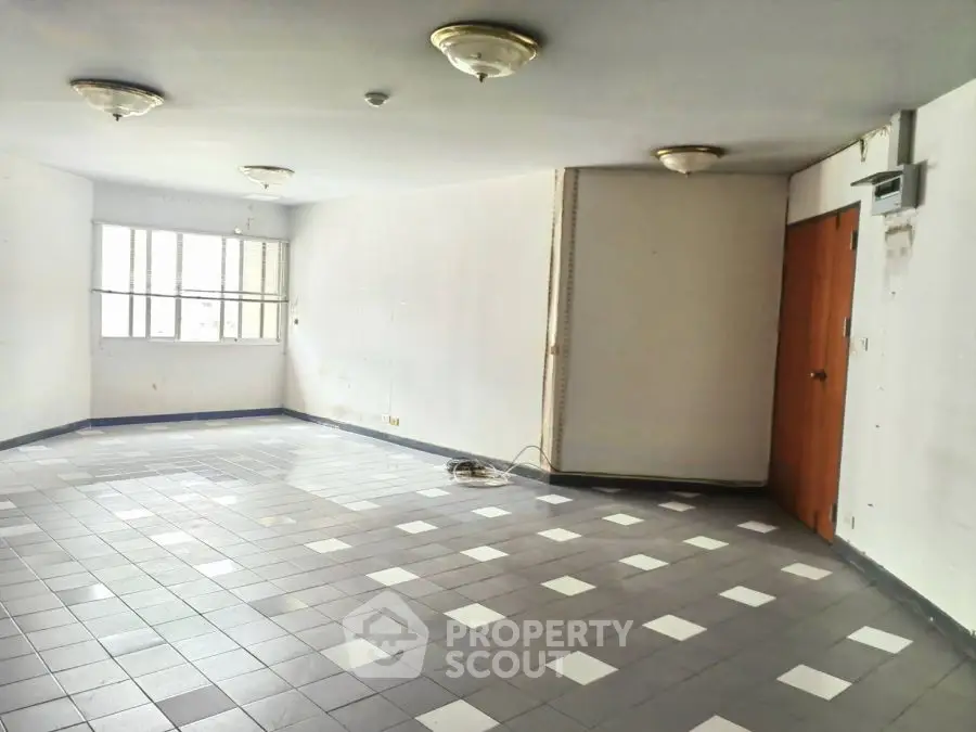 Spacious empty room with tiled floor and large window, ideal for customization.