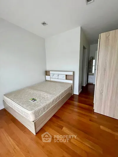 Spacious bedroom with wooden flooring and modern furnishings in a stylish apartment.
