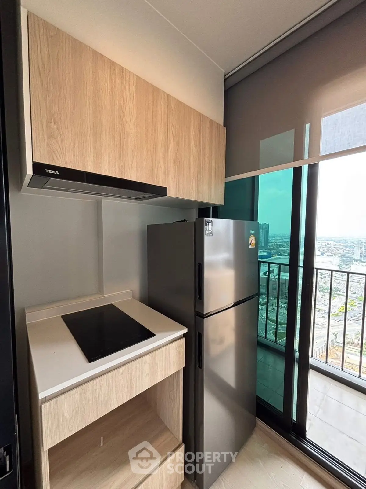 Modern kitchen with sleek appliances and balcony view in high-rise apartment