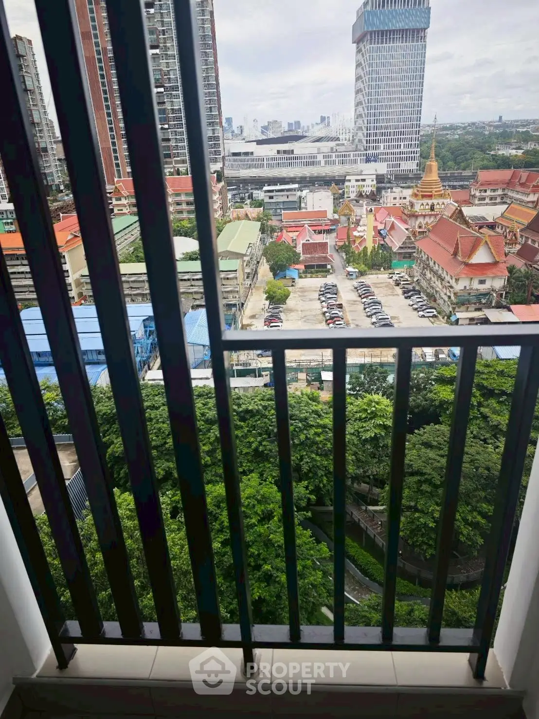 Stunning cityscape view from a high-rise balcony overlooking urban skyline and lush greenery.