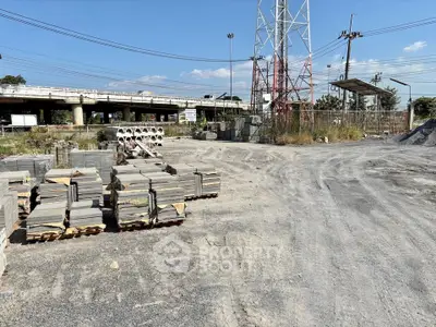 Spacious construction site with stacked building materials and clear blue sky.