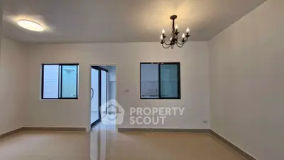 Spacious unfurnished room with chandelier and large windows, ideal for customization.