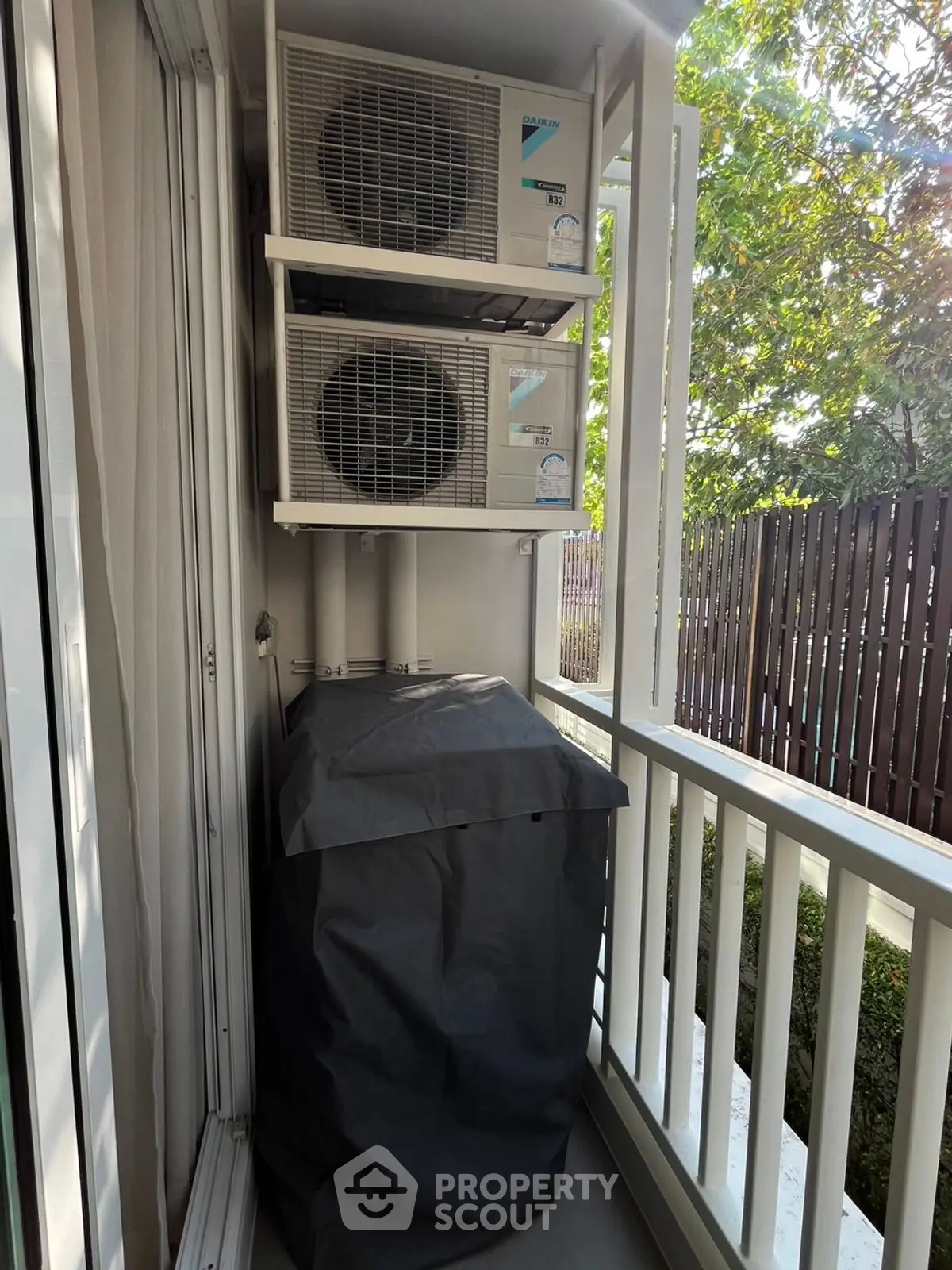 Compact balcony with air conditioning units and garden view
