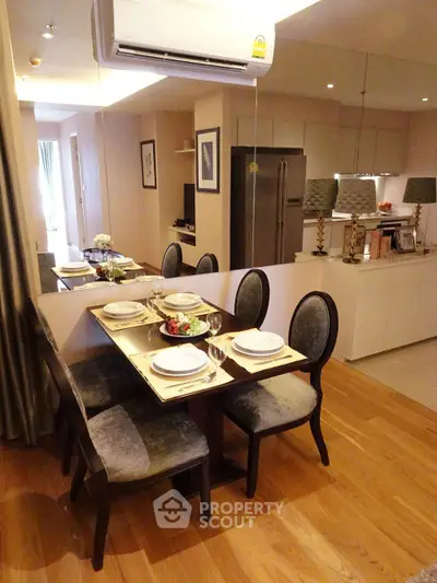 Elegant dining area with stylish table setting and modern kitchen in open layout apartment.