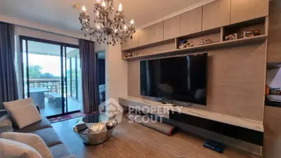 Luxurious living room with chandelier and large TV, opening to a spacious balcony with scenic views.
