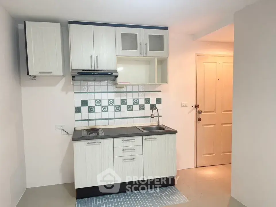 Compact kitchen with modern cabinetry and tiled backsplash in cozy apartment