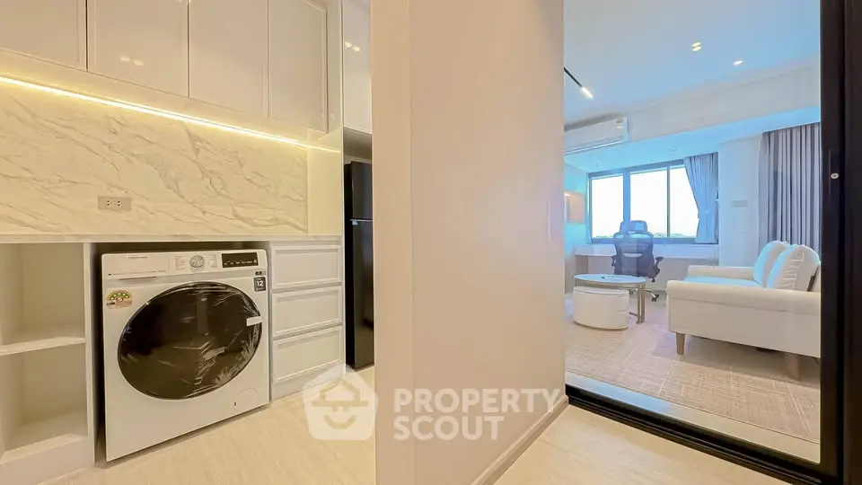 Modern apartment with open layout, featuring a sleek kitchen and cozy living area with natural light.