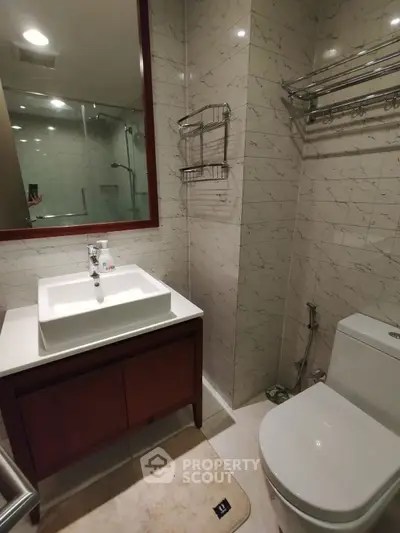 Modern bathroom with elegant fixtures and marble tiles, featuring a sleek vanity and spacious shower area.