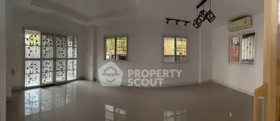 Spacious empty living room with large windows and modern lighting fixtures.