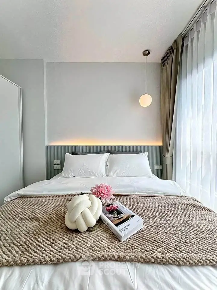 Modern bedroom with elegant decor and natural light, featuring a cozy bed and stylish lighting.