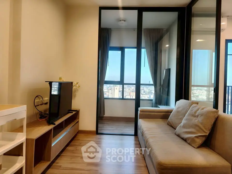 Modern living room with city view, featuring sleek glass doors and cozy seating area.