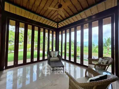 Luxurious living room with panoramic garden view and elegant wicker furniture.