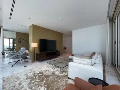Luxurious modern living room with stylish furniture and open layout, featuring a large TV and elegant decor.