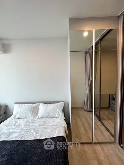 Modern bedroom with mirrored closet and cozy bedding in stylish apartment.