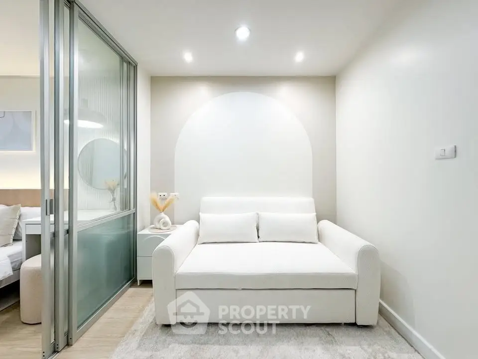 Modern living room with sleek white sofa and glass partition in stylish apartment.