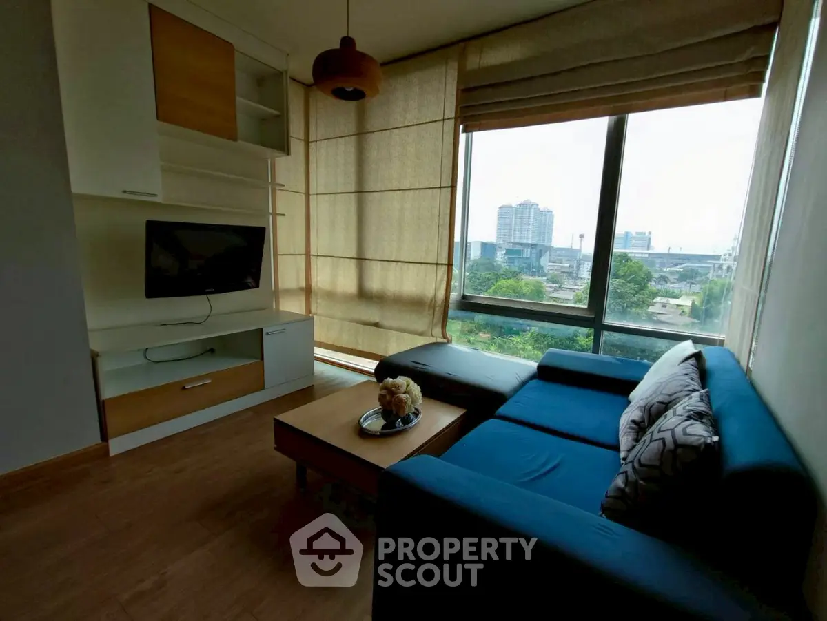 Modern living room with large window offering city view and stylish furniture.