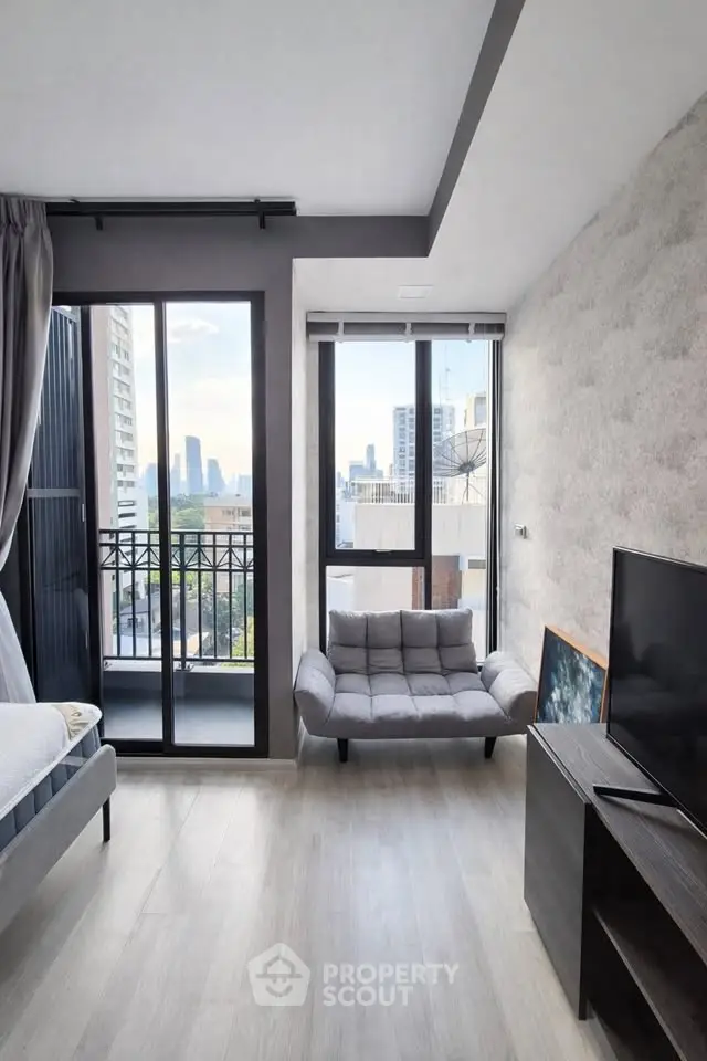 Modern living room with city view, featuring sleek furniture and large windows for natural light.