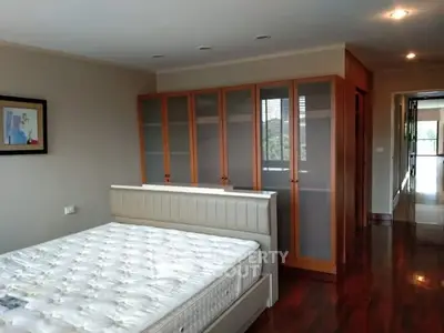 Spacious bedroom with wooden flooring and large wardrobe