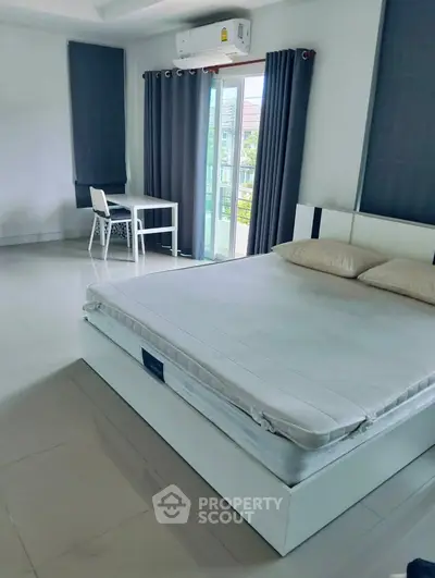 Spacious bedroom with modern decor and balcony access in a stylish apartment.
