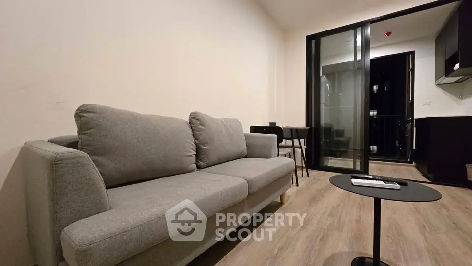 Modern living room with gray sofa and sleek black furniture, featuring a cozy balcony view.