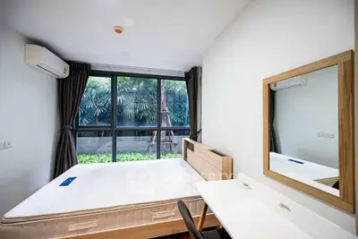 Modern bedroom with large window and garden view, featuring minimalist furniture and natural light.