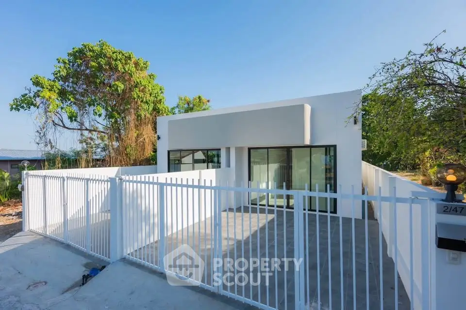 Modern minimalist white house with sleek design and spacious outdoor area.