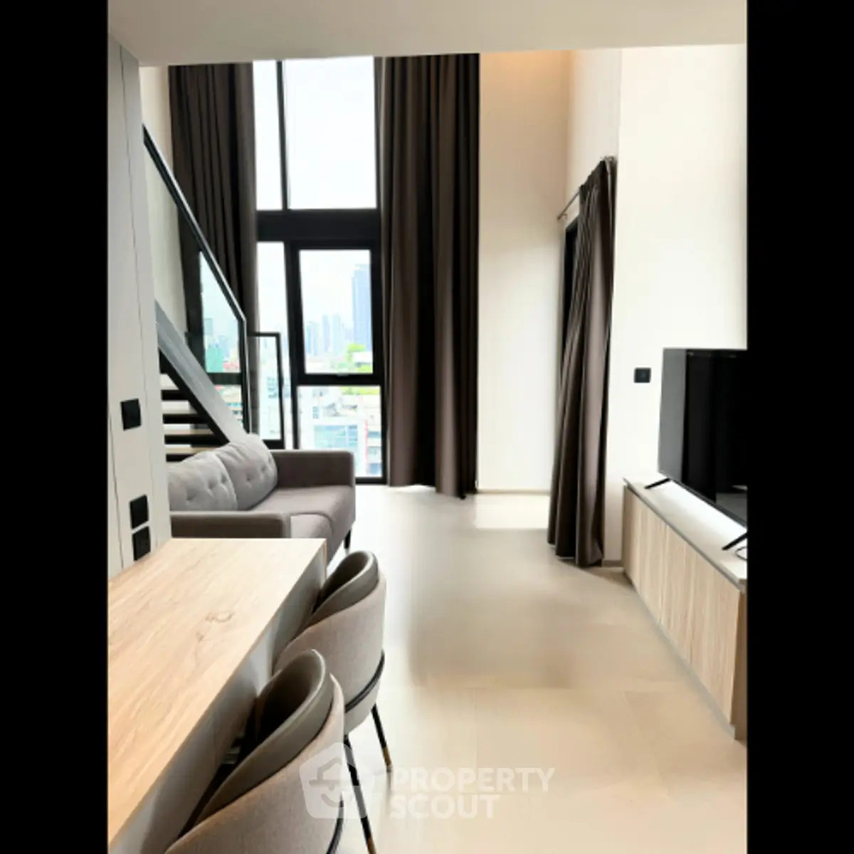 Modern duplex living room with high ceilings and city view, featuring stylish furniture and large windows.