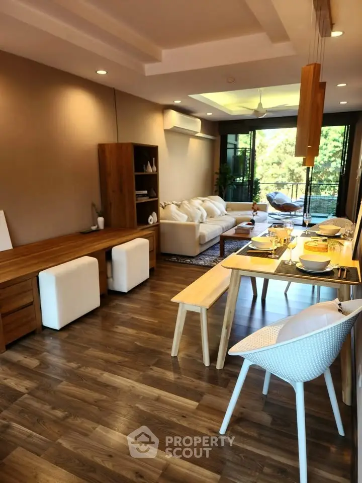 Spacious living room with elegant dining area and large windows overlooking greenery.