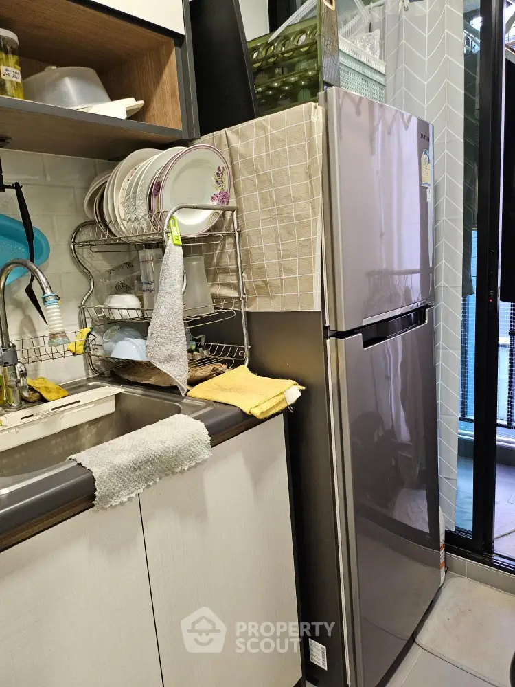 Compact kitchen with modern fridge and dish rack in cozy apartment