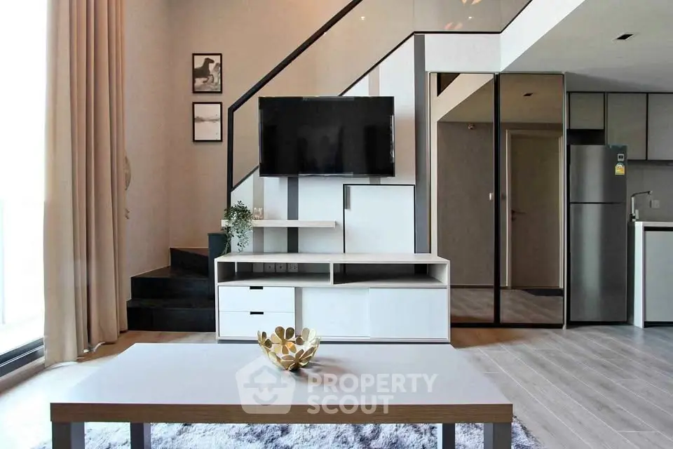 Modern living room with sleek staircase and stylish decor in a contemporary apartment.