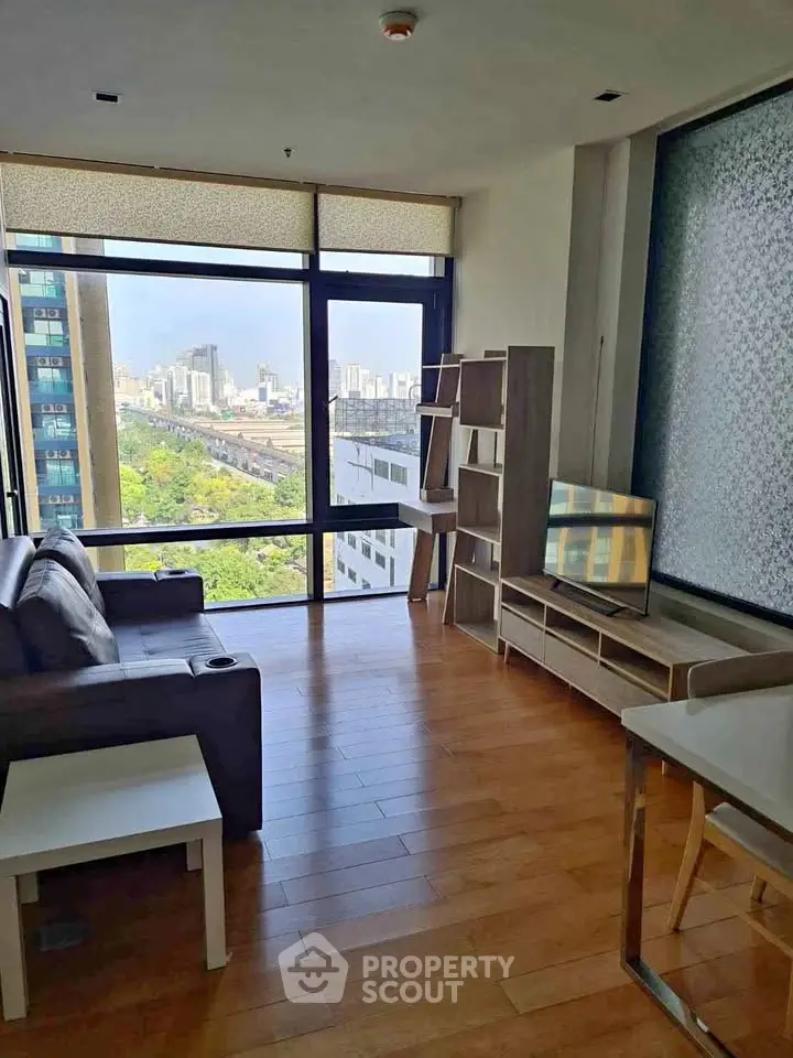 Modern living room with city view, stylish furniture, and large windows in a high-rise apartment.