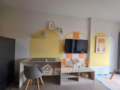 Modern living room with stylish decor, wall-mounted TV, and cozy workspace